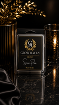 Glow Haven Snow Pixie clam shell wax melt in a black and gold labelled pack beside a glowing candle